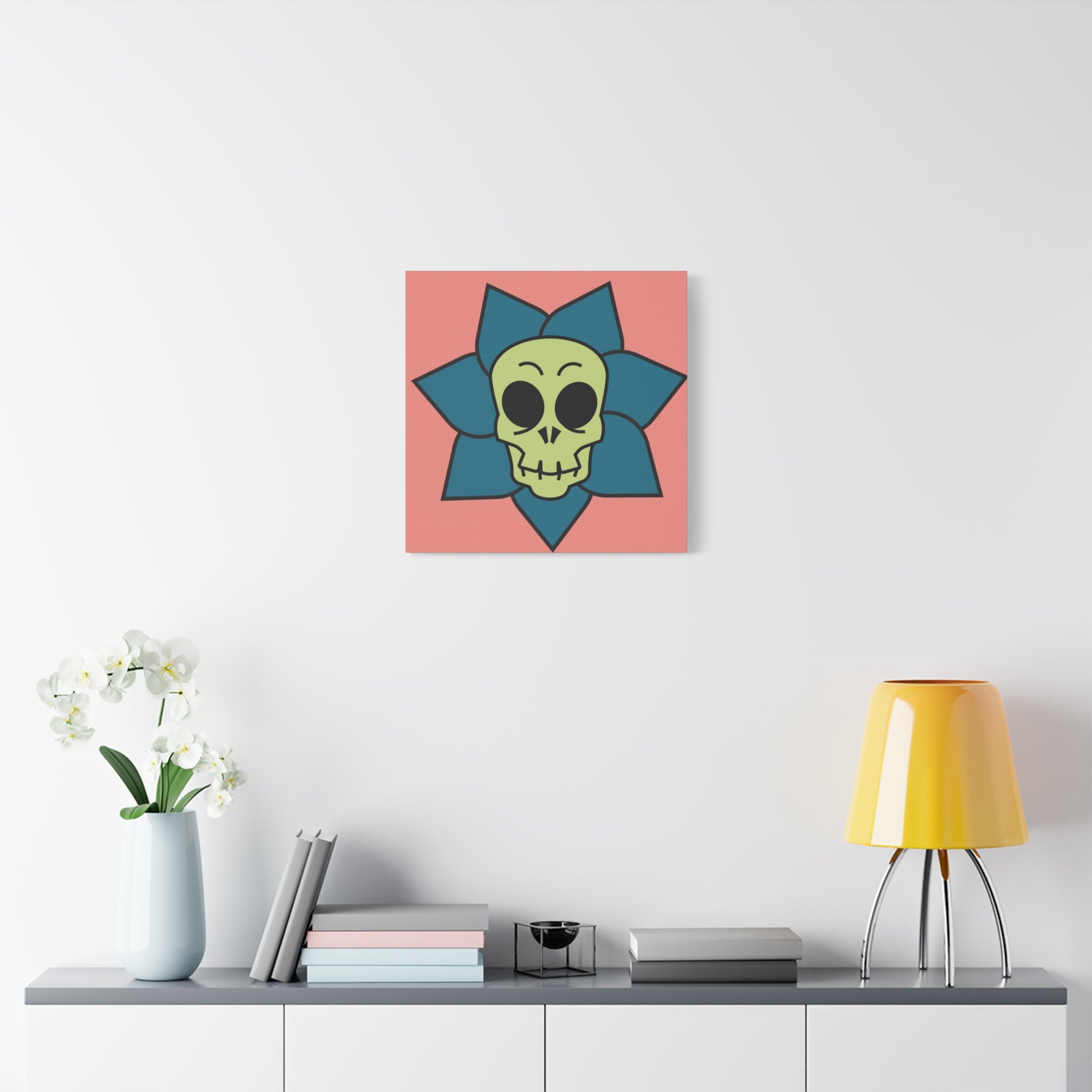 Decorative wall art with a skull design on a pink background, placed above a shelf with a lamp and books.